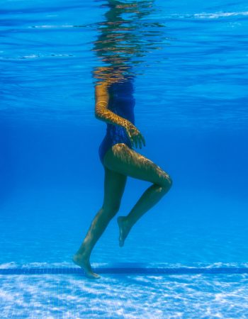 Underwater photo of an elegant young woman in a blue swimming suit relaxing
